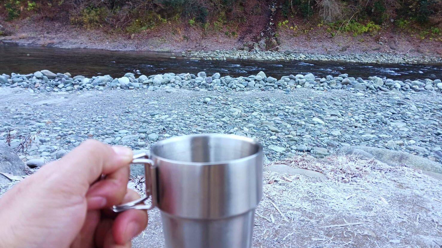 川辺でコップで水を飲んでいる画像
